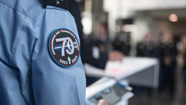 Photo en gros plan sur la rondache créée spécfiquement pour les 70 ans de la GTA. Il y a l'inscription "Gendarmerie des transports aériens" en arc de cercle autour du logo des 70 ans. Le logo est une piste d'aéroport qui passe par le centre du 0 et derrière le 7. Sur cette piste, il y a un avion qui décolle. En dessous, il y a la grenade de la gendarmerie avec les dates 1953-2023.