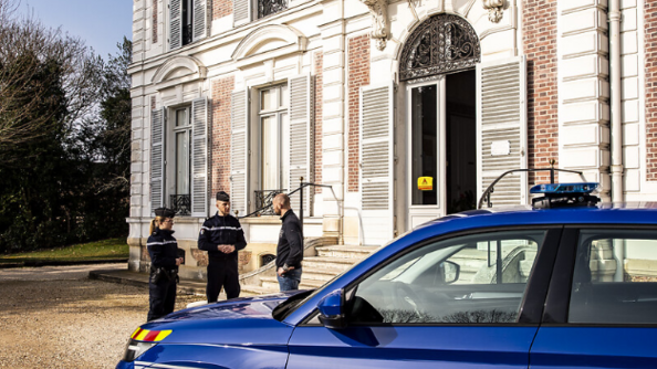 Au premier plan,  un véhicule gendarmerie. En arrière plan, deux gendarmes discutent avec un élu devant le bâtiment de la mairie.