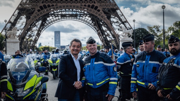 Des gendarmes motocylistes posent devant la Tour Eiffel en compagnie du ministre de l'Intérieur et des Outre-mer, Gérald Darmanin. Ce dernier serre la main de l'un des gendarmes.