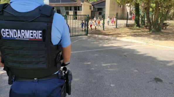 Un gendarme devant la cour de récréation d'une école.