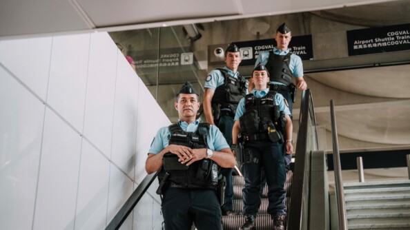 Quatre gendarmes descendent un escalator à l'aéroport