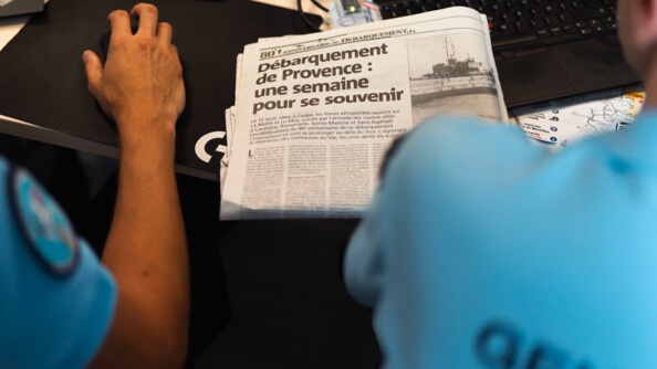 Photo montrant deux gendarmes de dos devant un journal titrant "Débarquement de Provence : une semaine pour se souvenir"
