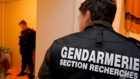Un enquêteur d'une section de recherches de dos avec le brassard gendarmerie.