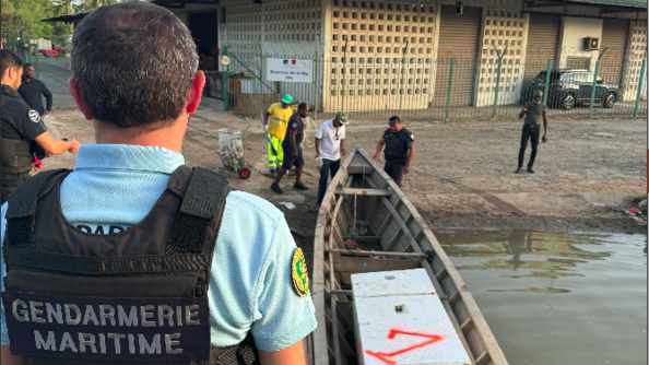 Gendarme surplombant l'embarcation contenant le frigo hors d'usage ramenée à terre.