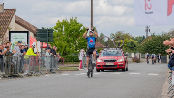 Un cycliste vainqueur à l'arrivé du 25e championnat de France de cyclisme gendarmerie lève les doigts vers le ciel.
