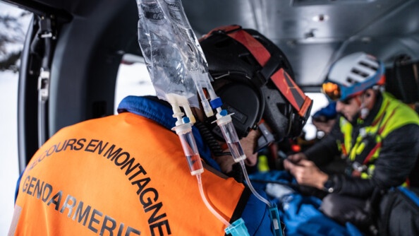 Un gendarme secouriste de dos dans l'hélicoptère en train de prendre en charge un patient.