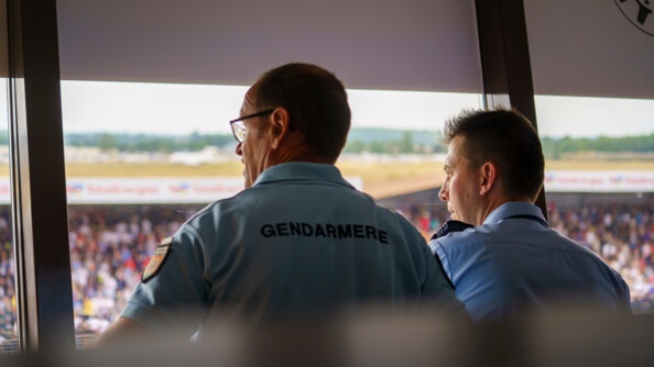 Le colonel et son adjoint reagarde par la fenêtre qui donne sur le circuit.