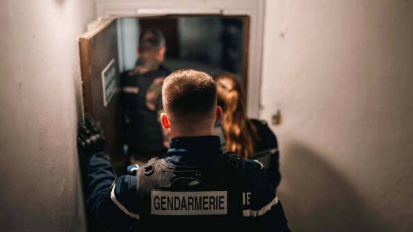 Trois gendarmes &eacute;voluent dans le sous-sol d'un immeuble. Ils se tiennent de dos par rapport &agrave; l'objectif. L'un d'eux tient une porte tandis que les deux autres p&eacute;n&egrave;trent dans une pi&egrave;ce.