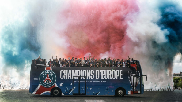Photo du bus des footballeurs du PSG, avec sur le flanc du véhicule l'inscription "Champions d'Europe". des fumées bleues, blanches et rouges ont été tirées juste derrière le bus..