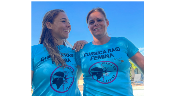 Deux femmes d'une quarantaine d'années, souriantes, posent côte à côte, vêtues du même t-shirt bleu portant l'inscription CORSICA RAID FEMINA. l'une d'elle pose sa main sur l'épaule de la seconde femme, regardant dans sa direction.