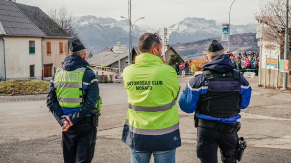 Deux gendarmes échangent avec un coordinateur de la course, de la sécurisation de celle ci. En fond, on voit les montagnes.