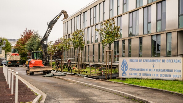 Image d'un grand b&acirc;timent gris, devant lequel est appos&eacute;e une grande pancarte portant l'inscription en lettres bleues sur fond blanc "R&eacute;gion de gendarmerie de Bretagne". Des engins de travaux manoeuvrent dans l'all&eacute;e deva,nt le b&acirc;timent.