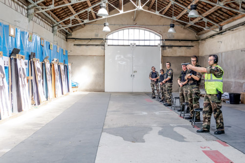 Des élèves s'entraînent dans un stand de tir. L'un d'eux s'apprête à tirer sur une cible.