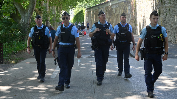 Cinq gendarmes effectuent une patrouille pédestre dans la rue, à l'occasion du festival Garorock. Les cinq militaires avancent côte à côte.
