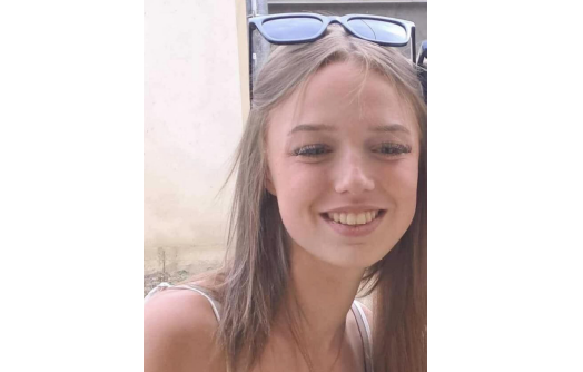 Photo montrant Lina, jeune fille aux cheveux châtains, souriante, portant des lunettes de soleil sur la tête et un haut blanc.