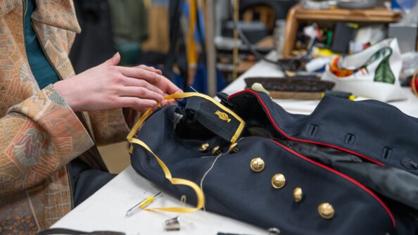 Plan rapproch&eacute; des mains de la couturi&egrave;re cousant une veste de Garde.