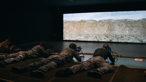 Quatre gendarmes et militaires en treillis allongés sur le sol avec leur FAMAS; exercice de tir vers un écran au mur