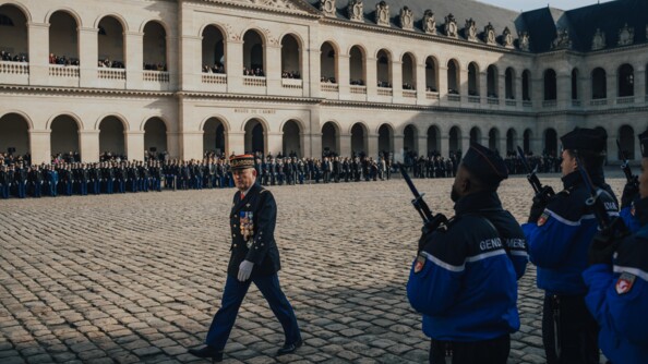 Le directeur général de la gendarmerie marche devant ses troupes dans la cour pavée des invalides