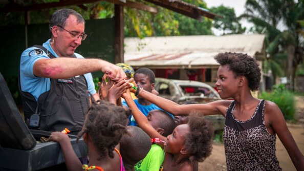 Commandant en second de la compagnie donnant des friandises aux enfants d'un quartier informel.