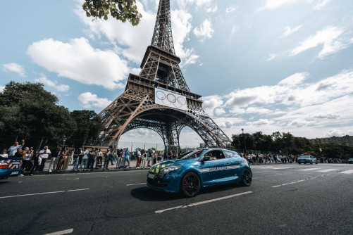 Une voiture de la gendarmerie passe devant la Tour Eiffel, sur laquelle sont aposés les anneaux olympiques