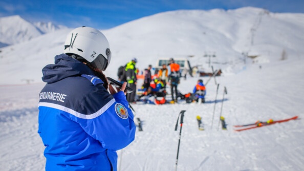 Gendarme au t&eacute;l&eacute;phone avec l'accident de ski en fond.